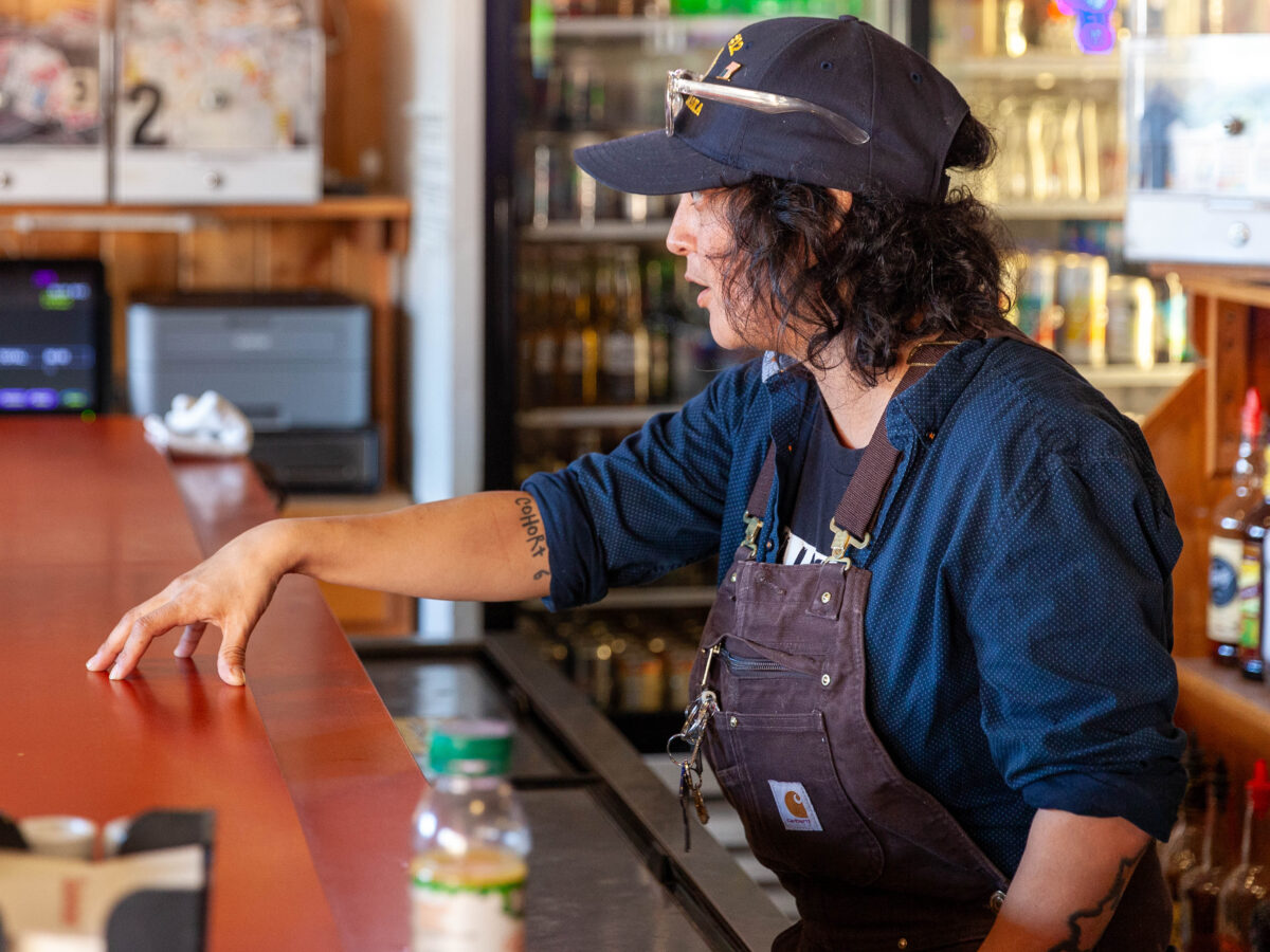Jessica Gutierrez talks to customers while bartending on Wednesday, March 27, 2024, in Haines, Alaska. Gutierrez, is a veteran who had to work for months to get her medical benefits reinstated once she got into town. (Photo by Rashah McChesney/Chilkat Valley News)