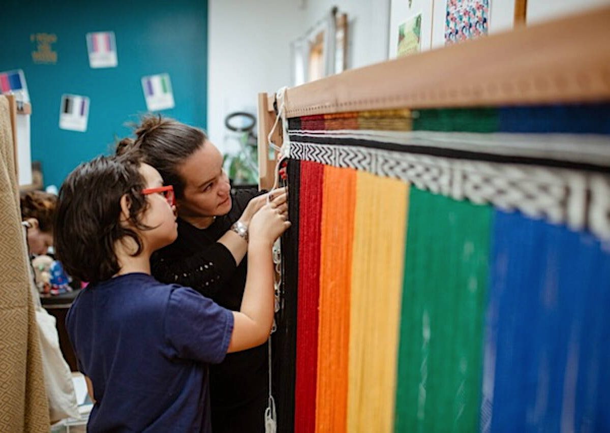 Lily Hope (right) teaches a student how to weave Ravenstail on the Youth Pride Robe project. (Photo courtesy of Lily Hope)