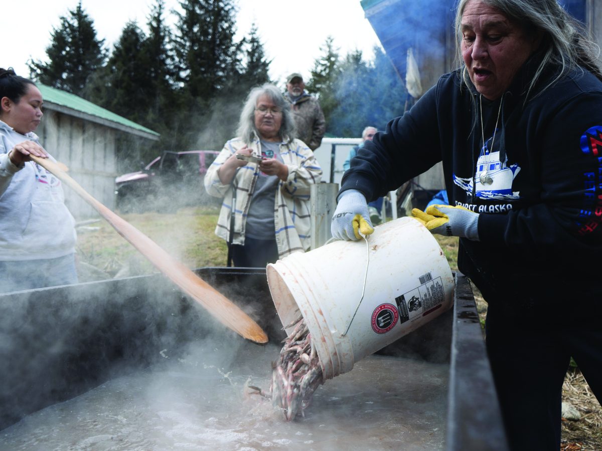 Dori Thompson pours hooligan into a heating tank on May 2, 2024, at the Lkoot Kwáan culture camp. (Lex Treinen/Chilkat Valley News)