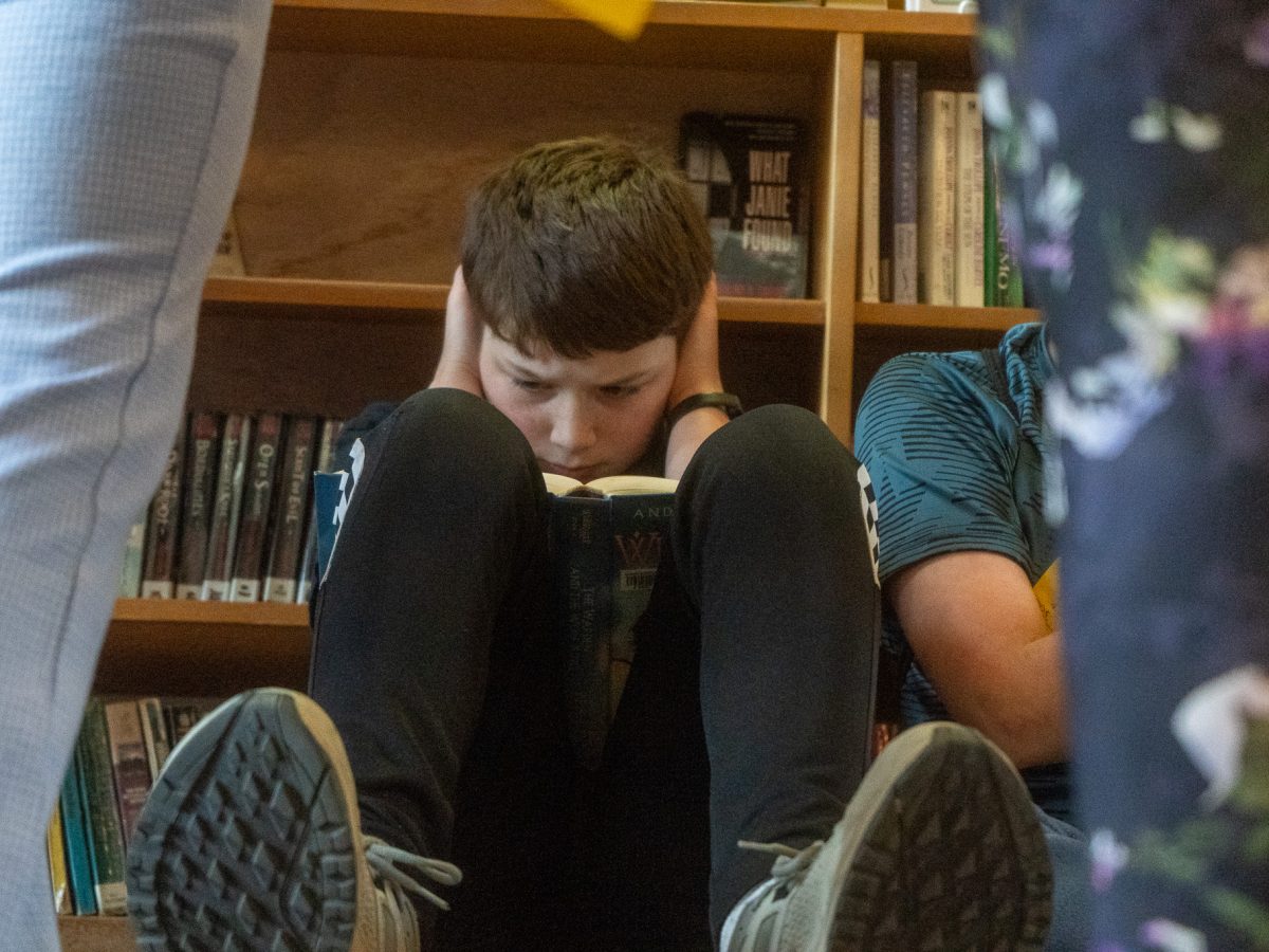 Grady Robinson covers his ears to focus while waiting in line for the summer reading prize giveaway. (Lex Treinen/Chilkat Valley News)