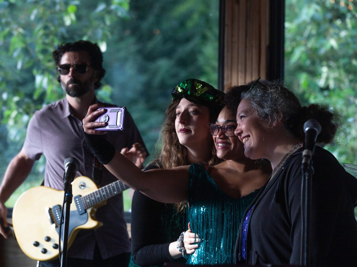 Taylor Vidic, Salissa Thole, and Shona Strauser pose for a photo before performing with High Costa Living during a community-wide wedding reception for Henry Pollan and Ela Sokolowska on Saturday, July 20, in Haines, Alaska. (Rashah McChesney/Chilkat Valley News)