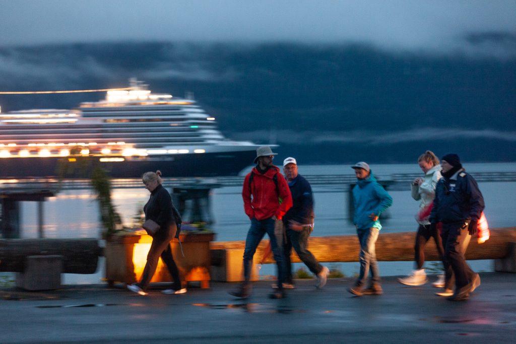 Passengers jump off of a bus and headed down Haines' cruise ship dock toward a nearby Holland America cruise ship on Wednesday, July 24, 2024, in Haines, Alaska. About 150 people, primarily cruise ship passengers who had disembarked in Skagway, were trapped by a landslide in Canada and then bussed several hundred miles to Haines to rejoin their cruises. (Rashah McChesney/Chilkat Valley News)