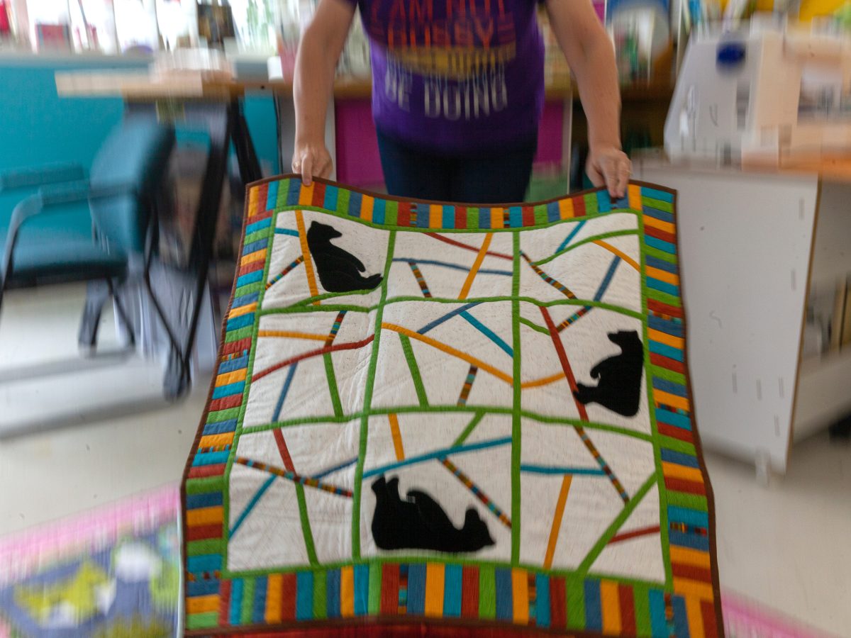Carol McConahy shows one of the quilts available for auction during the 2024 Southeast Alaska State Fair in Haines, Alaska. Proceeds from the auction will go to the Haines Hot Shots. (Rashah McChesney/Chilkat Valley News)