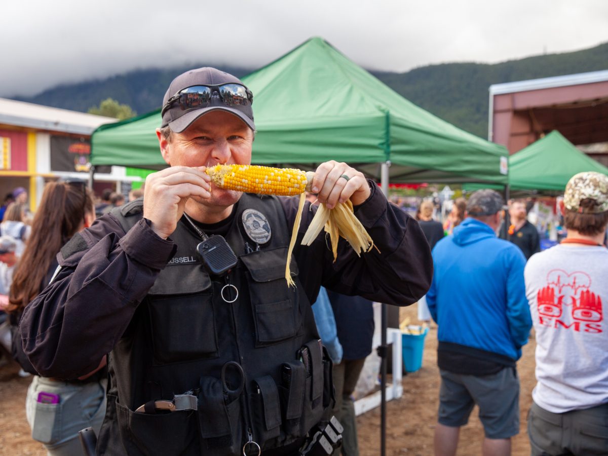 A police officer bites into an ear of corn.