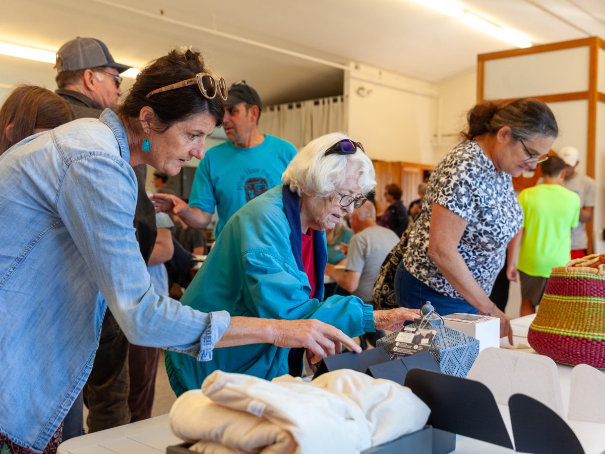 Jesse Crow (left) and Nora Krake look at items in a silent auction benefitting Natalie Benassi. (Rashah McChesney/Chilkat Valley News)