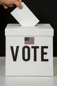 A hand placing a blank ballot into a ballot box