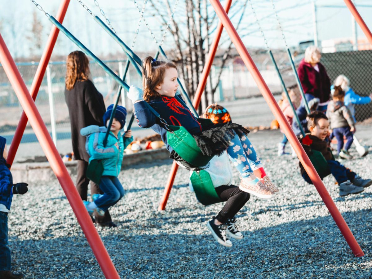 Students swing on a playground at Meadow Lakes Head Start in Wasilla, Alaska. It closed this year due to funding and staffing challenges. (Image by Lela Seiler, courtesy of CCS Early Learning)