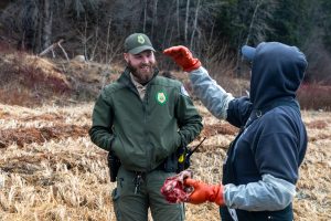 State Park Ranger Jacques Turcotte (left) talks to Tim Ackerman about what may have killed it, on Friday, Jan. 24, 2024, on the Letnikof Cove shoreline. (Rashah McChesney/Chilkat Valley News)
